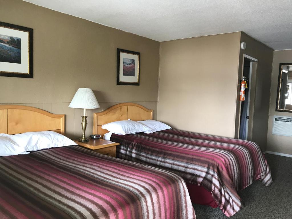 a hotel room with two beds and a lamp at Bulkley Valley Motel in New Hazelton