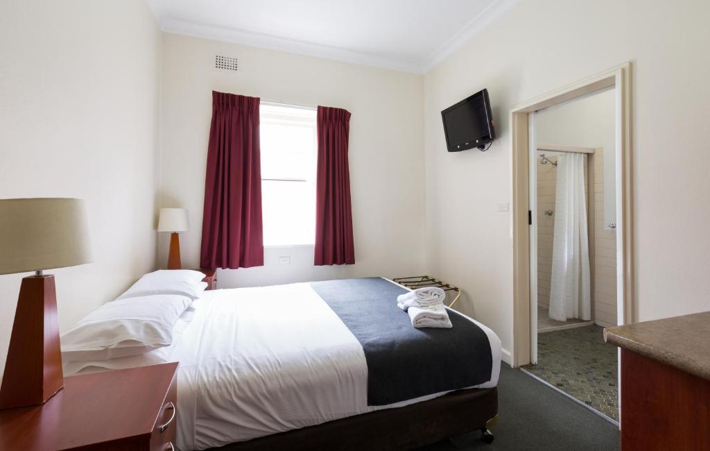 a hotel room with a large bed with red curtains at Knickerbocker Hotel in Bathurst