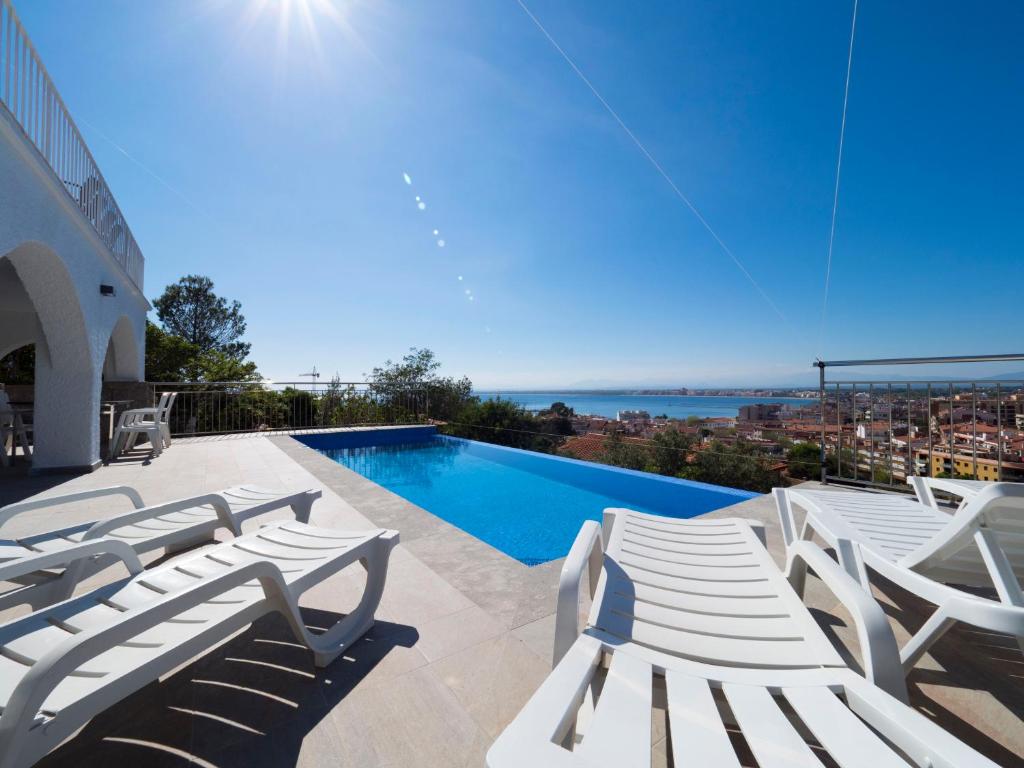 een groep witte ligstoelen en een zwembad bij InmoSantos Casa Tordera in Roses