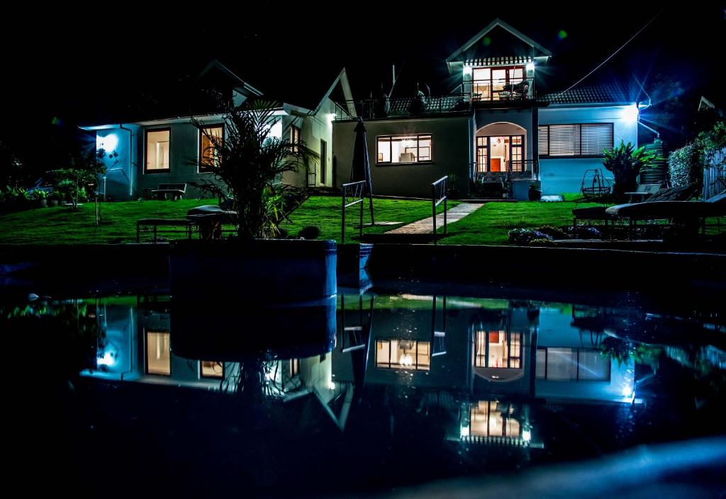 a house at night with its reflection in the water at Senate Guest House in Knysna
