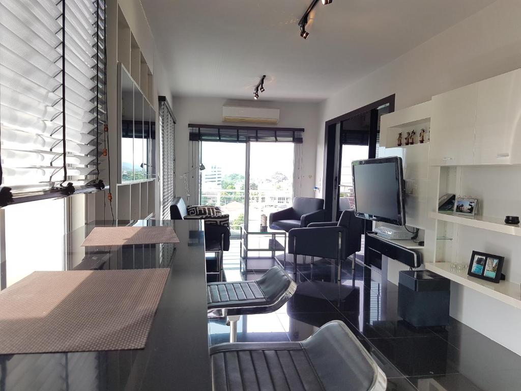 Habitación con sillas, mesas y TV. en Flame Tree Residence 2-Bedroom Apartment, en Hua Hin