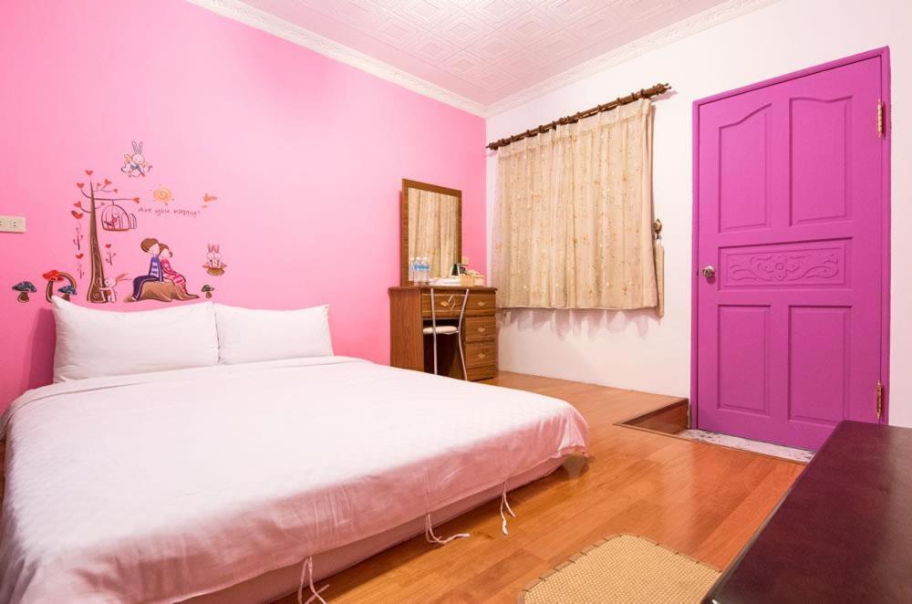 台東市的住宿－狗窩民宿，一间卧室设有一张大床和紫色的门