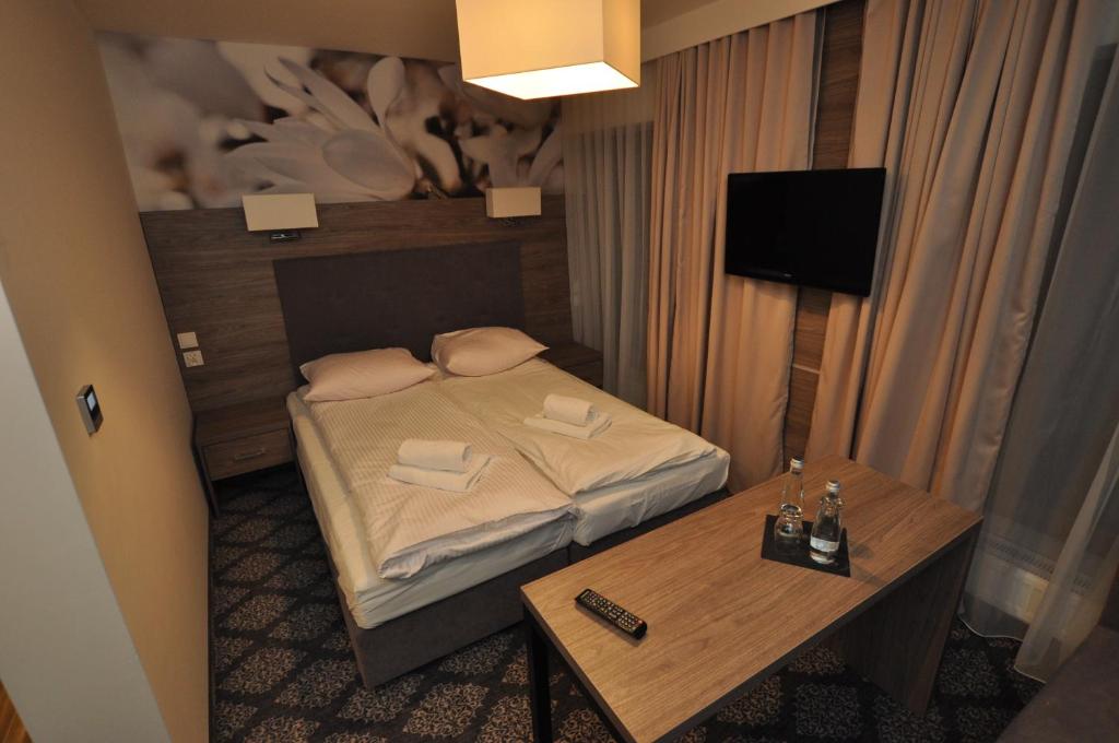 niewielka sypialnia z łóżkiem i stołem w obiekcie Pass Hotel w mieście Zebrzydowice