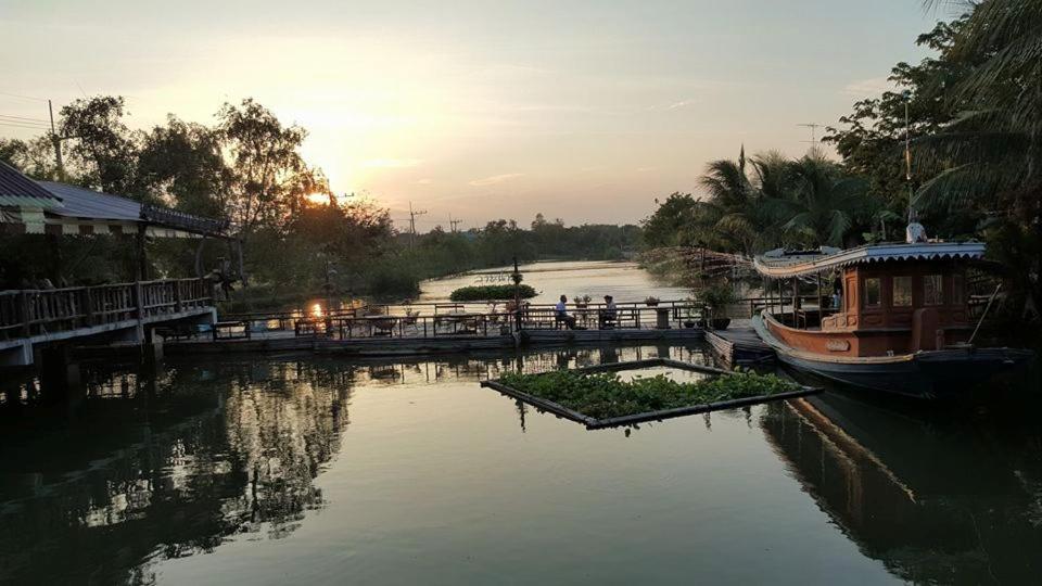 a river with a pier and a boat in the water at Country Lake View Hotel in Suphan Buri
