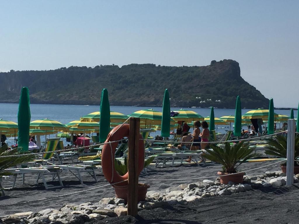 a beach with chairs and umbrellas and people on the beach at Casello sul Mare in San Nicola Arcella
