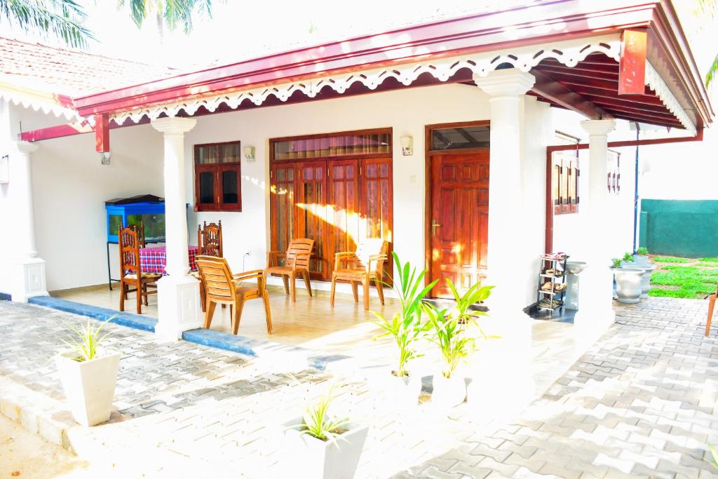 Ein weißes Haus mit einer Terrasse mit Stühlen und Tischen in der Unterkunft Marcelin Family Villa in Negombo