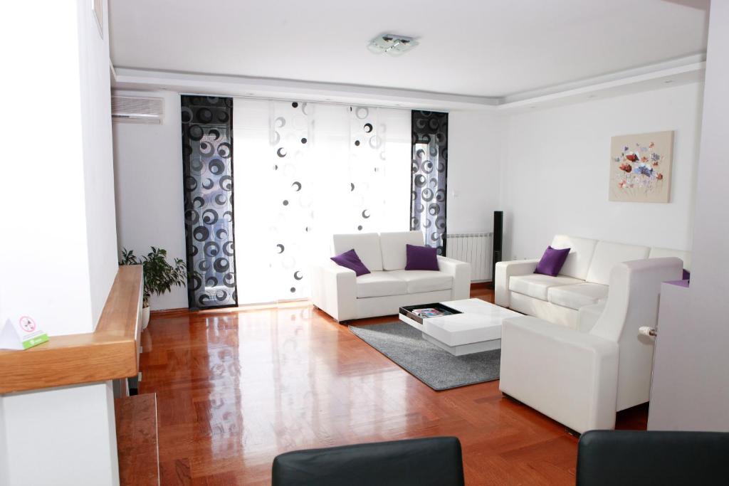 ein Wohnzimmer mit weißen Möbeln und lila Kissen in der Unterkunft Apartmani Nova in Karlovac