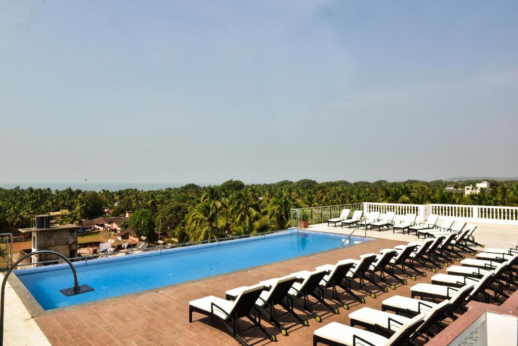 a large swimming pool with lounge chairs on a resort at Silver Sands Serenity in Candolim