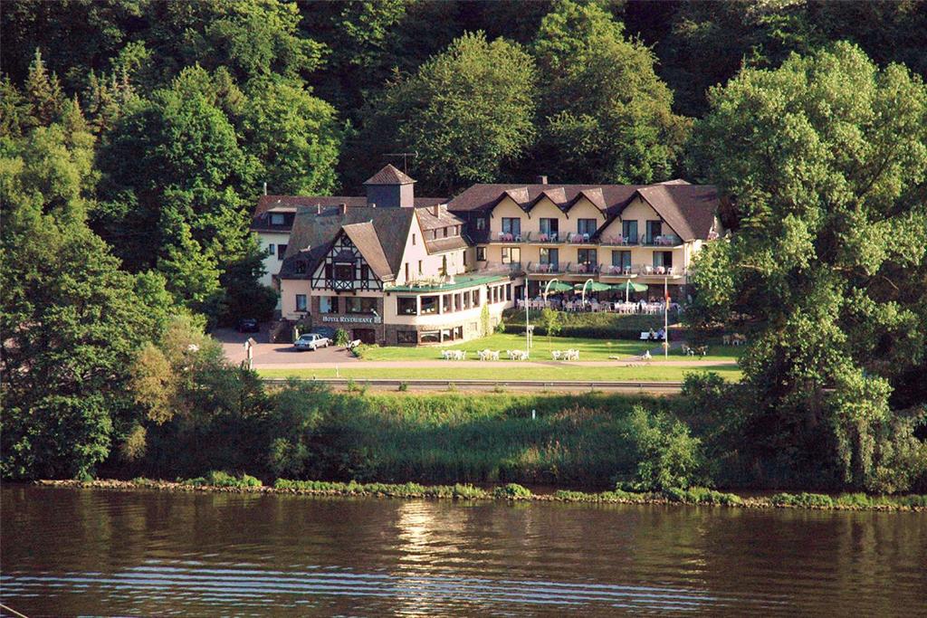 een groot huis aan de oever van een rivier bij Hotel-Restaurant Peifer in Brodenbach