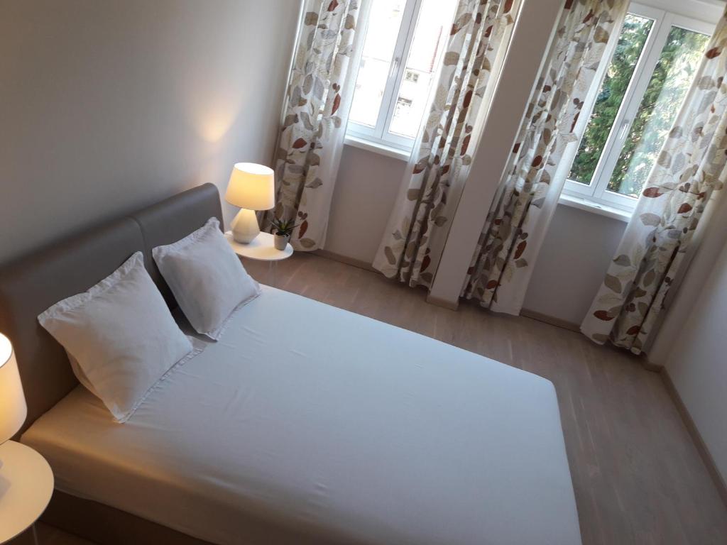 a bedroom with a large bed with two windows at City Center Apartment in Valjevo