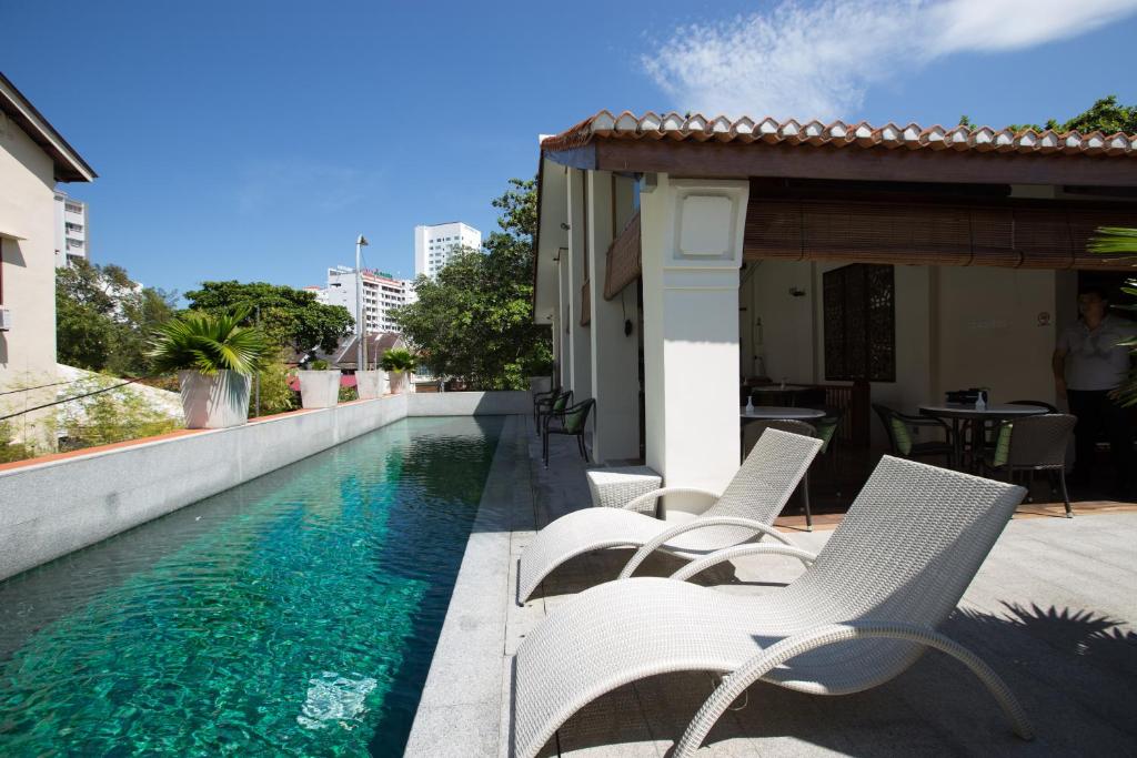 a group of white chairs sitting next to a swimming pool at Muntri Grove in George Town