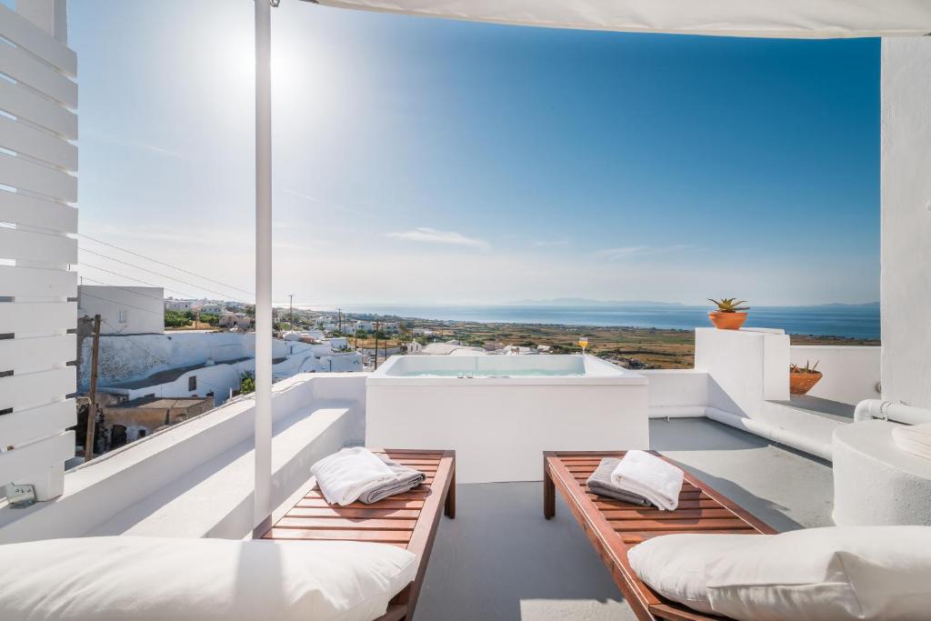 balcón con muebles blancos y vistas al océano en Fava Eco Suites, en Oia