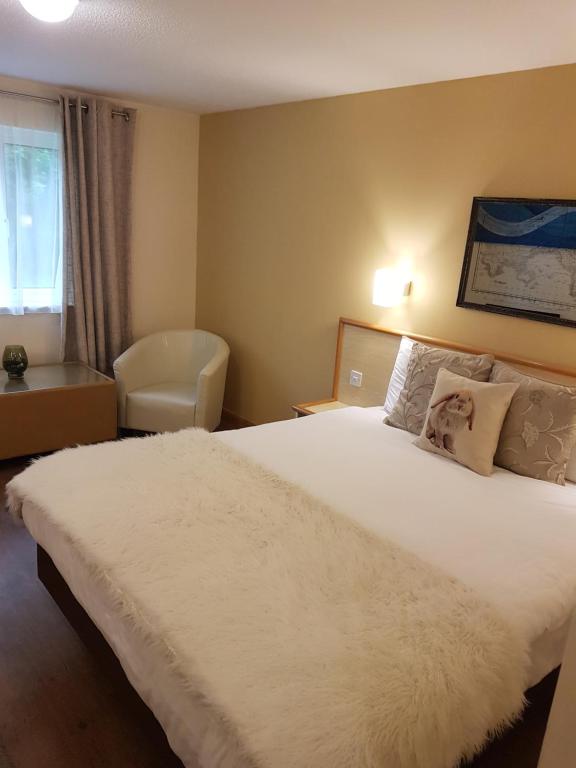 a bedroom with a large white bed and a chair at Travel Plaza Hotel in Desborough