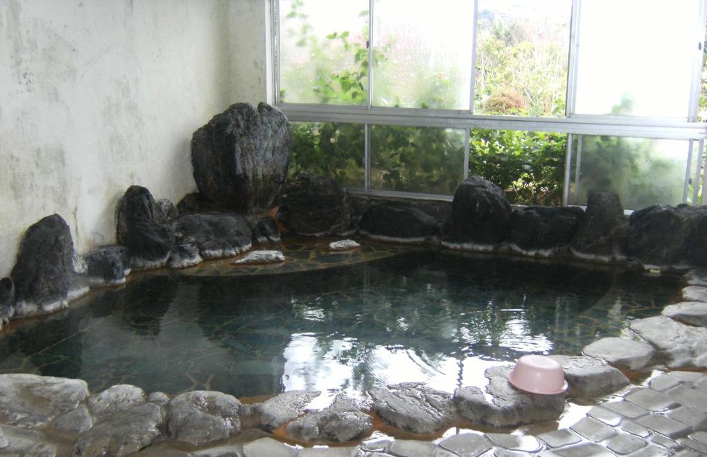 una piscina di acqua con rocce in una stanza con finestre di YOKOSO Ryokan a Beppu