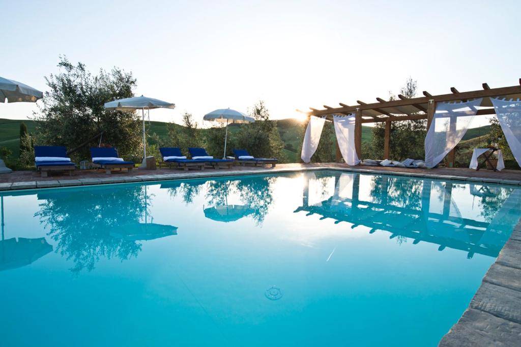 a swimming pool with blue water and blue chairs at Agriturismo Podere Campaini in Volterra