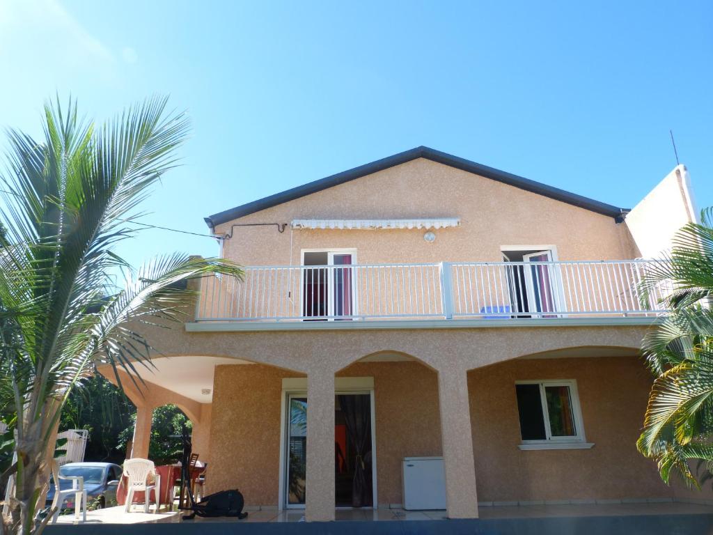 a house with a balcony and a palm tree at Chez Chouchou in Rivière