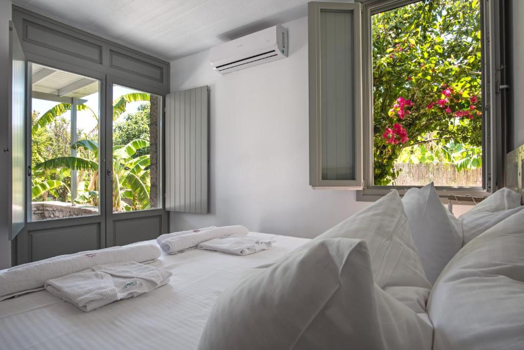 uma cama branca com almofadas brancas e 2 janelas em Melagrana em Adamas