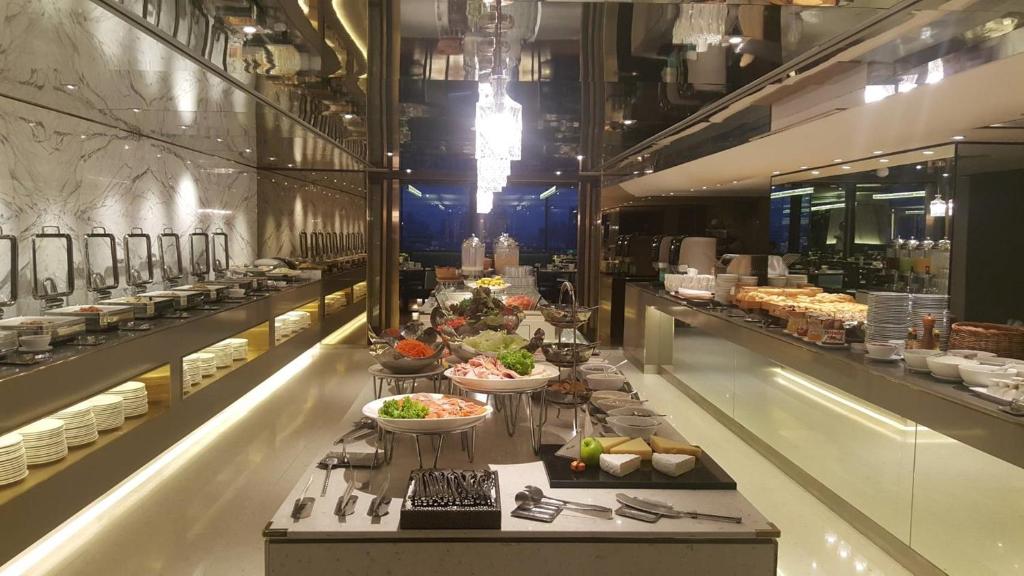 A long buffet counter presents salads, prepared dishes, bread and tableware in a sleek mirrored dining area.