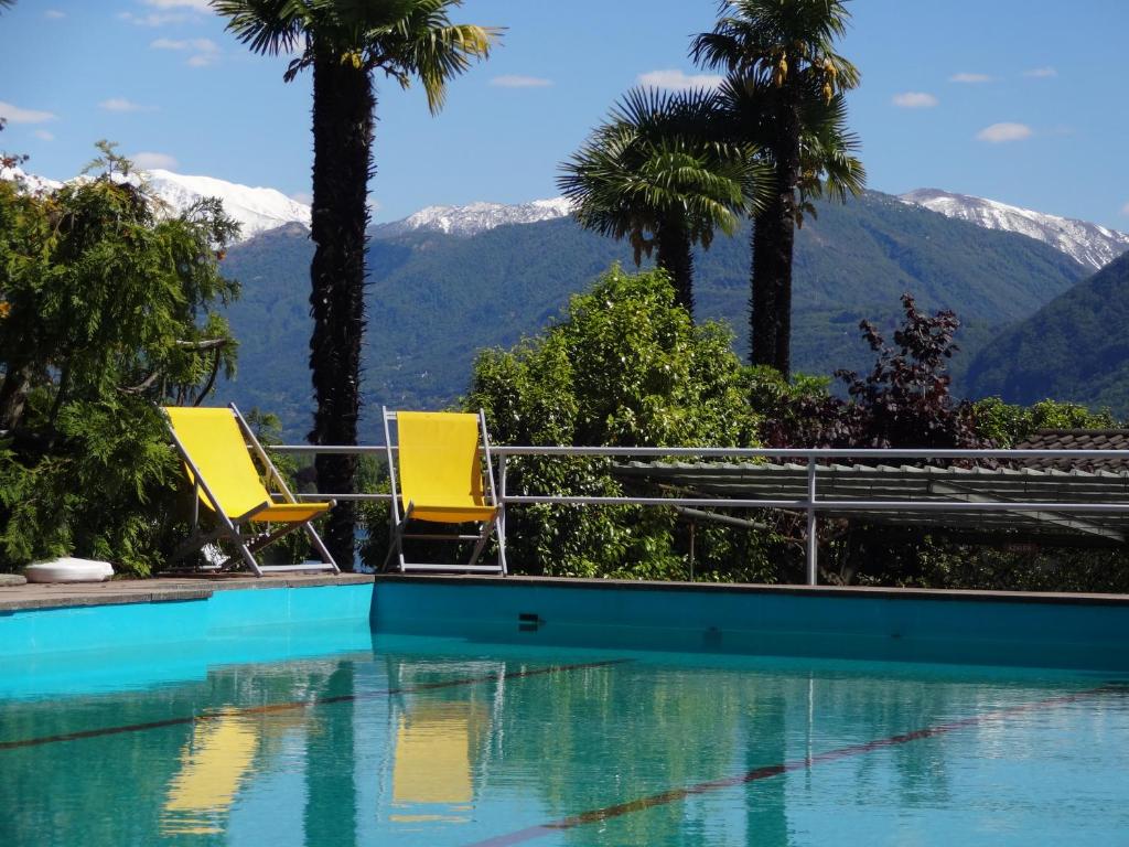 two yellow chairs sitting next to a swimming pool with mountains at Residenza Paradiso di Vacanze in Locarno