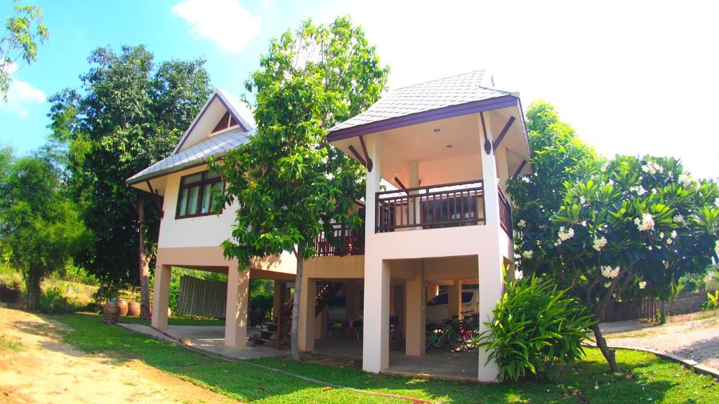 a house with a balcony in the yard at Baan2rai in Kanchanaburi