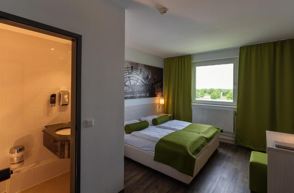 a hotel room with a bed and a bathroom at LifeHotel Vienna Airport in Fischamend Dorf