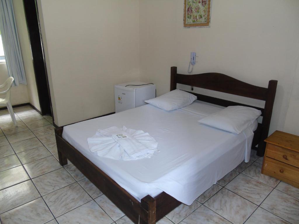 1 dormitorio con 1 cama con sábanas blancas y vestidor en Novo Hotel Douglas, en Balneário Camboriú