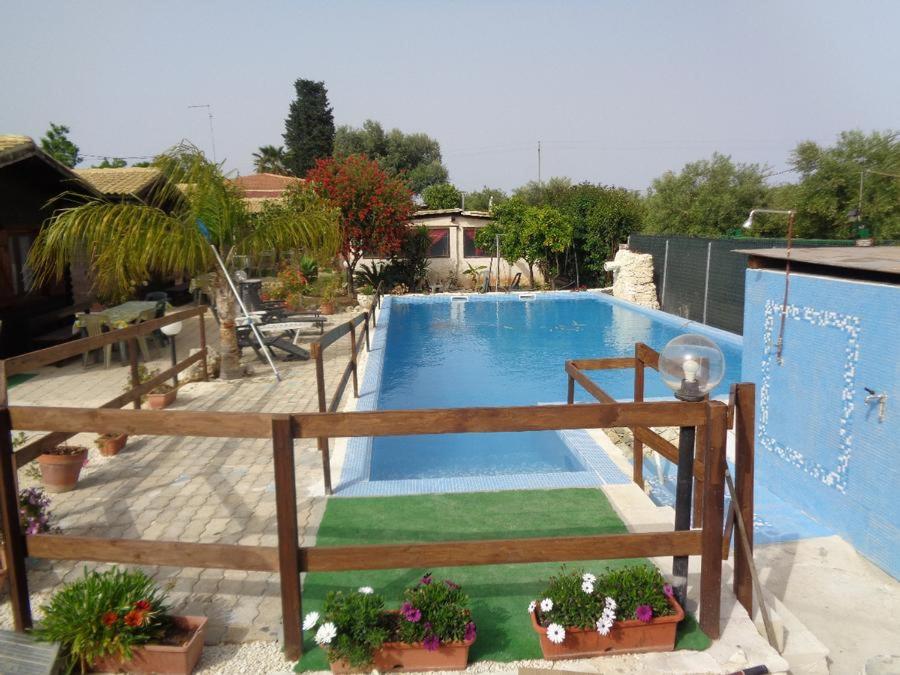 a large swimming pool with a wooden fence and plants at Bungalow Janet in Cassibile