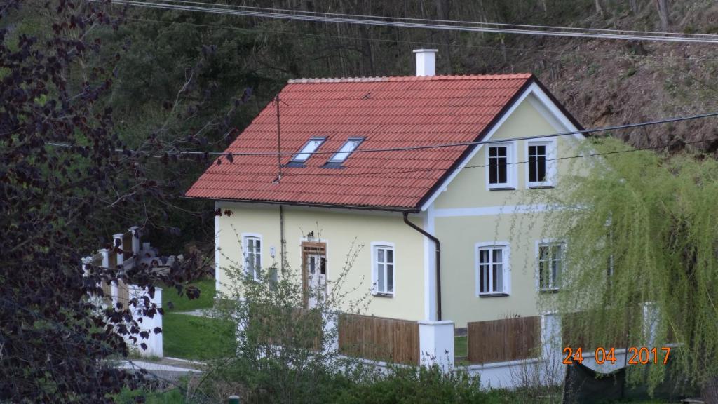 una pequeña casa blanca con techo rojo en Chaloupka za potůčkem, en Županovice