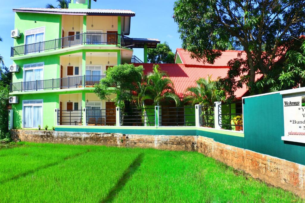 a house with a green lawn in front of it at Nature Resort in Tissamaharama