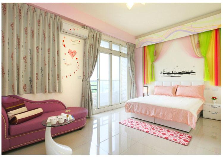 a bedroom with a pink bed and a purple couch at Hong Lai Guest House in Jiaoxi