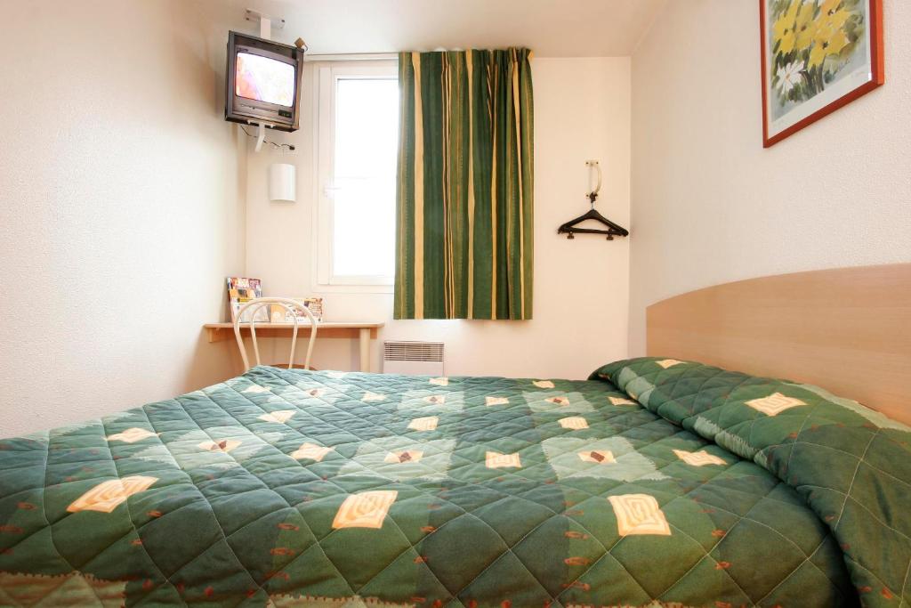 1 dormitorio con 1 cama con edredón verde y ventana en Premiere Classe Dunkerque Loon Plage, en Loon-Plage