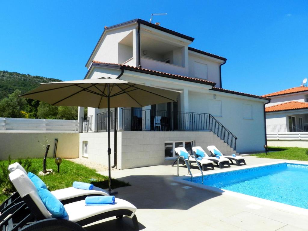 a pool with chairs and an umbrella next to a house at VILLA AURA YourCroatiaHoliday in Drenje
