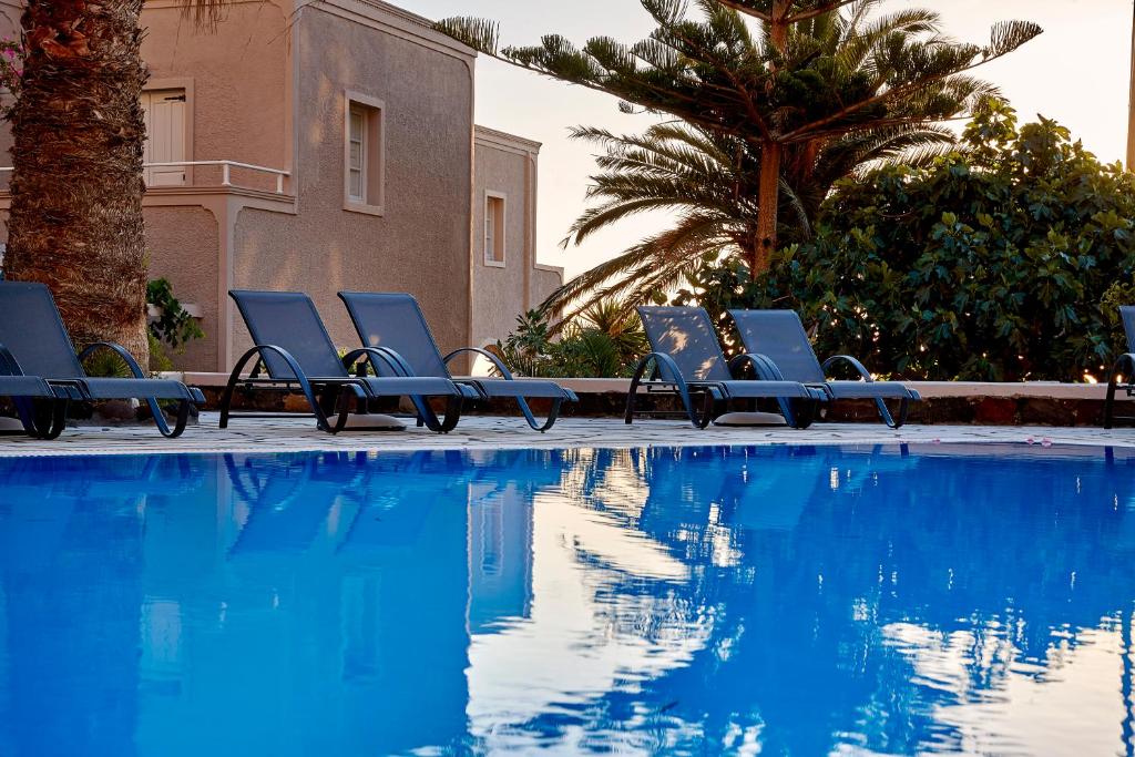 a group of blue lounge chairs next to a swimming pool at Terra Blue Santorini in Kamari