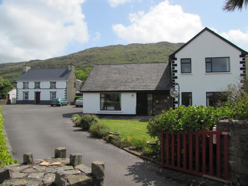 una casa blanca y una casa con montañas en el fondo en An Dooneen, The Hurley Farm B&B, en Ballydavid