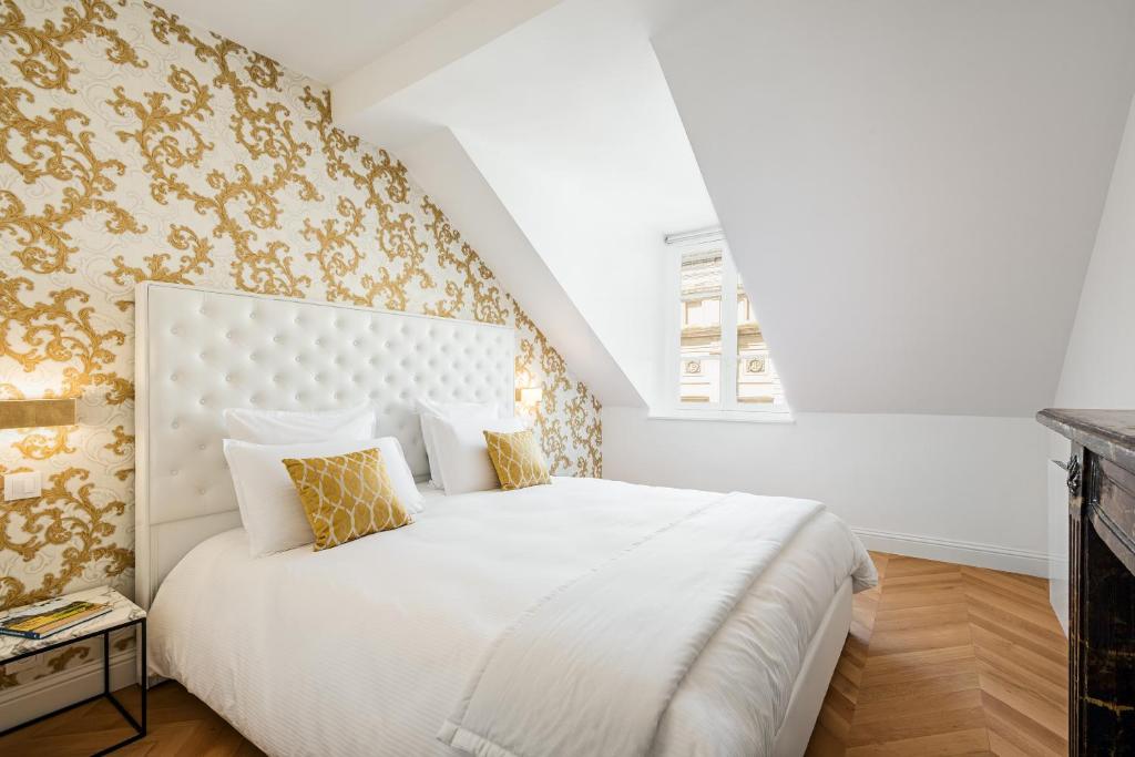 um quarto com uma grande cama branca com papel de parede dourado em Les Demoiselles à Versailles - Au Pied du Château em Versalhes