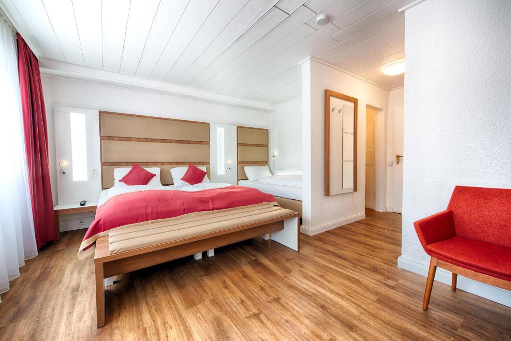 a bedroom with a red bed and a red chair at Hotel Senator in Dortmund