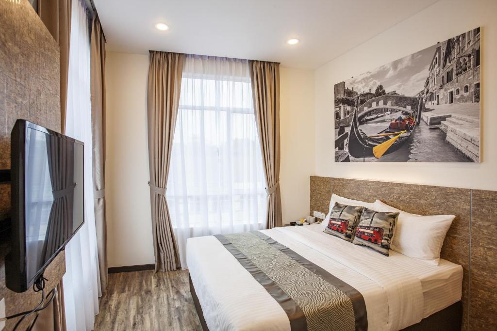 Schlafzimmer mit einem Bett, einem TV und einem Fenster in der Unterkunft Natura Hotel in Nusajaya