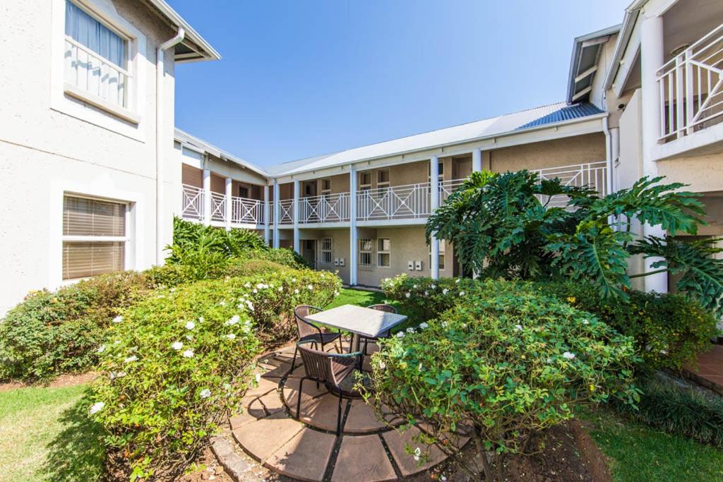 een terras met een tafel en stoelen voor een gebouw bij Vetho 2 Apartments OR Tambo Airport in Kempton Park