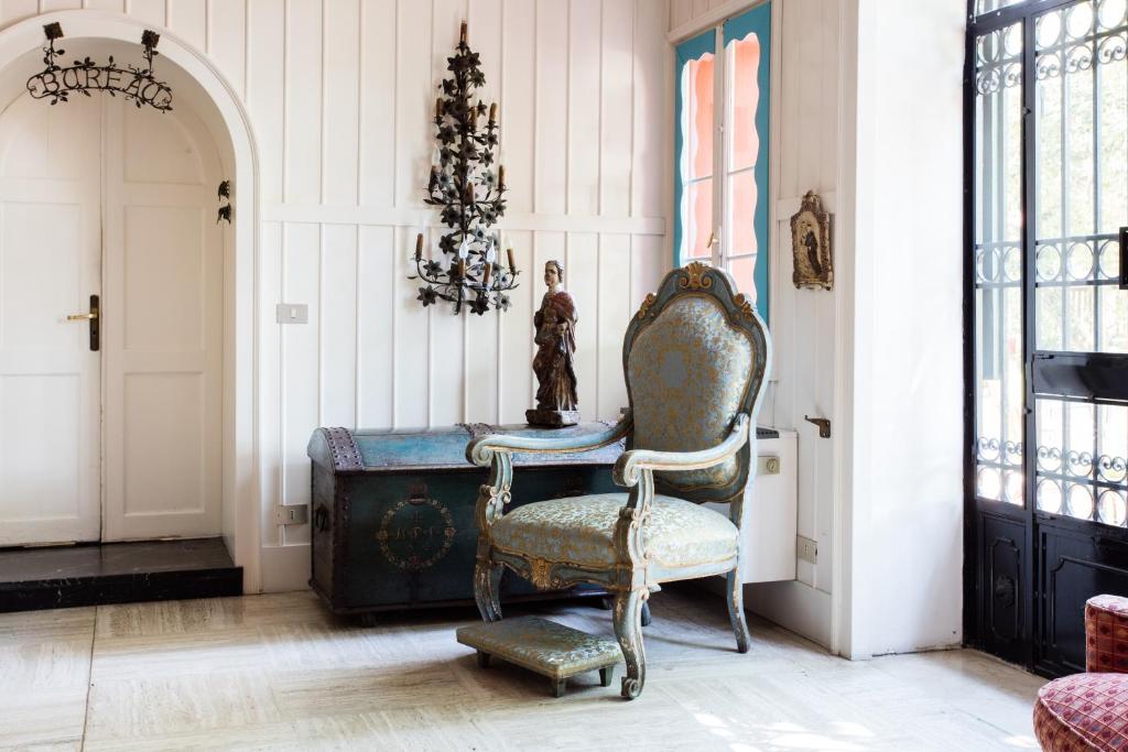 a chair in a room with a table and a chandelier at Residenza d'Epoca Albergo Quattro Fontane in Venice-Lido