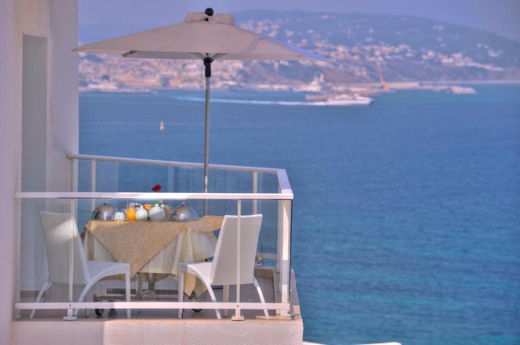 a table with an umbrella on a balcony with the ocean at Hotel Farah Tanger in Tangier