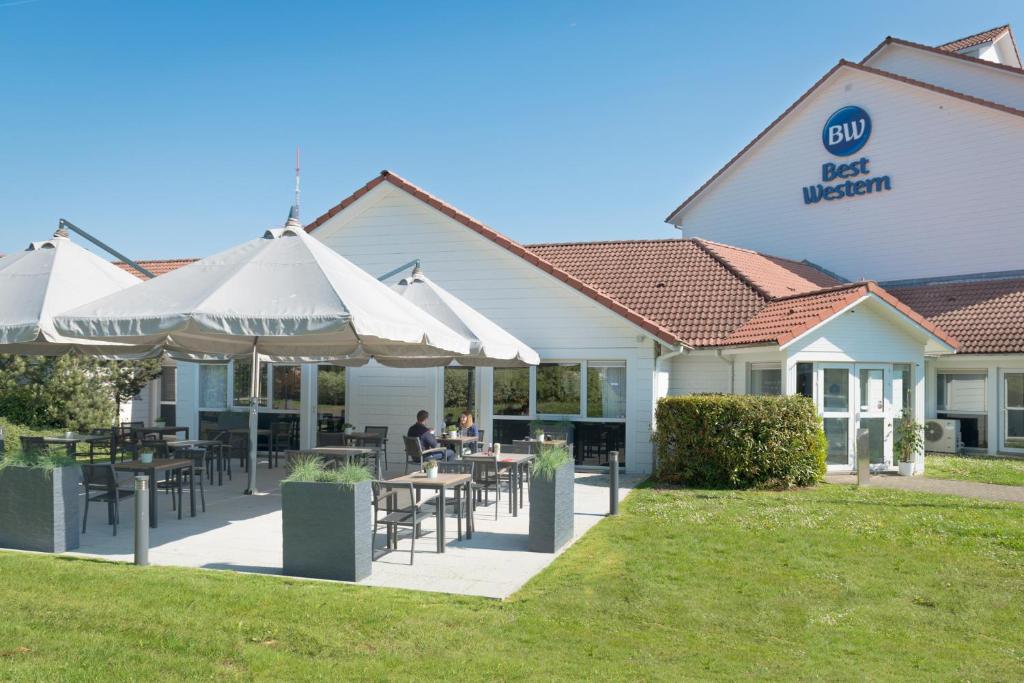 a restaurant with tables and umbrellas in front of a building at Best Western Hotel Wavre in Wavre
