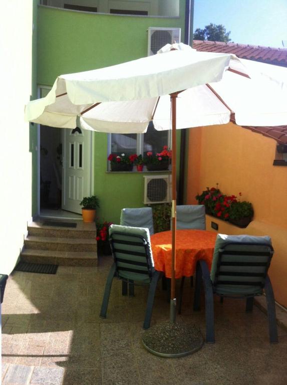 stół i krzesła z parasolem przed budynkiem w obiekcie Apartment Beni w Medulinie