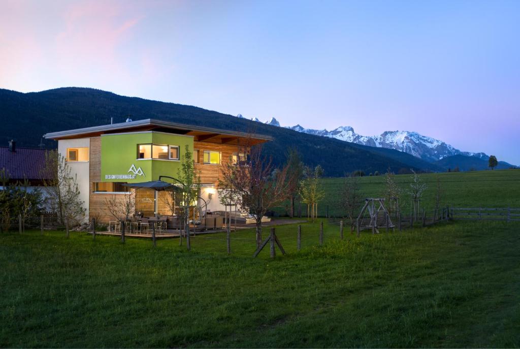 una casa in un campo con montagne sullo sfondo di Designferienhaus Altenmarkt Zauchensee a Altenmarkt im Pongau