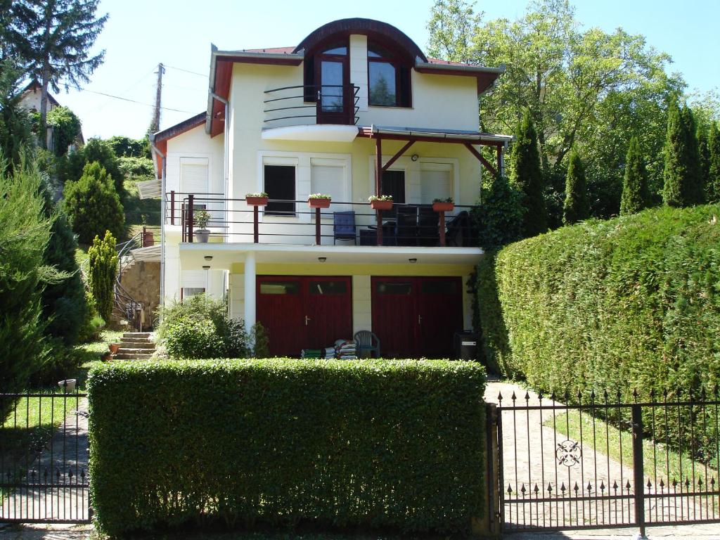 uma casa branca com portas vermelhas e sebes verdes em Biro Apartman em Zalakaros