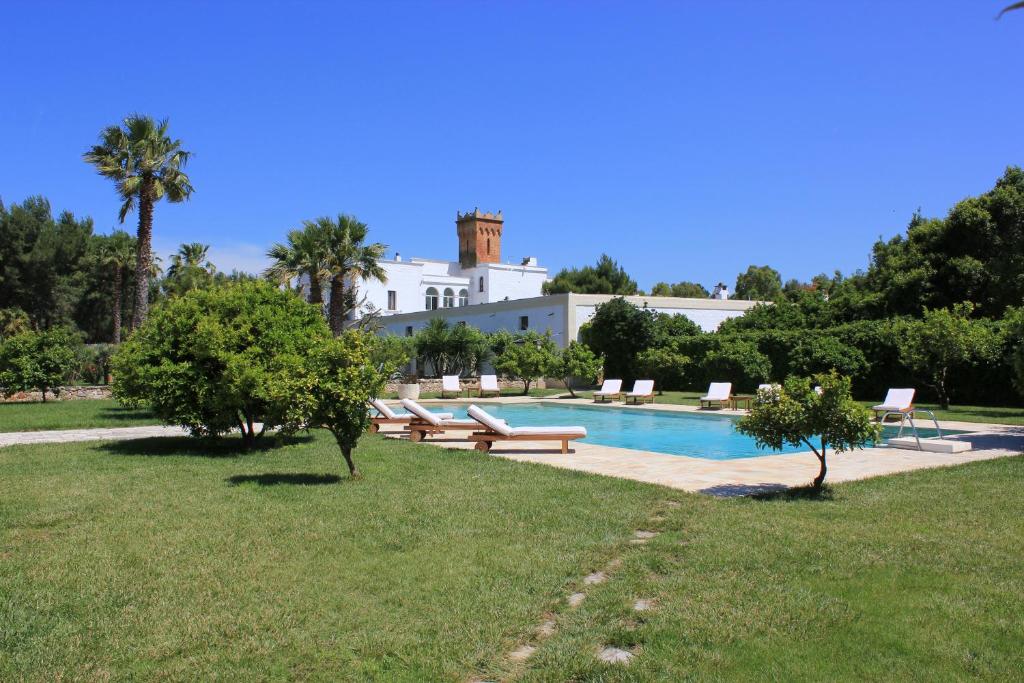 une piscine avec bancs et une maison en arrière-plan dans l'établissement Masseria Incantalupi, à San Vito dei Normanni