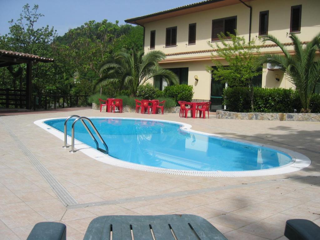 une piscine avec des chaises rouges et une maison dans l'établissement Hotel Chiar Di Luna, à Laino Borgo