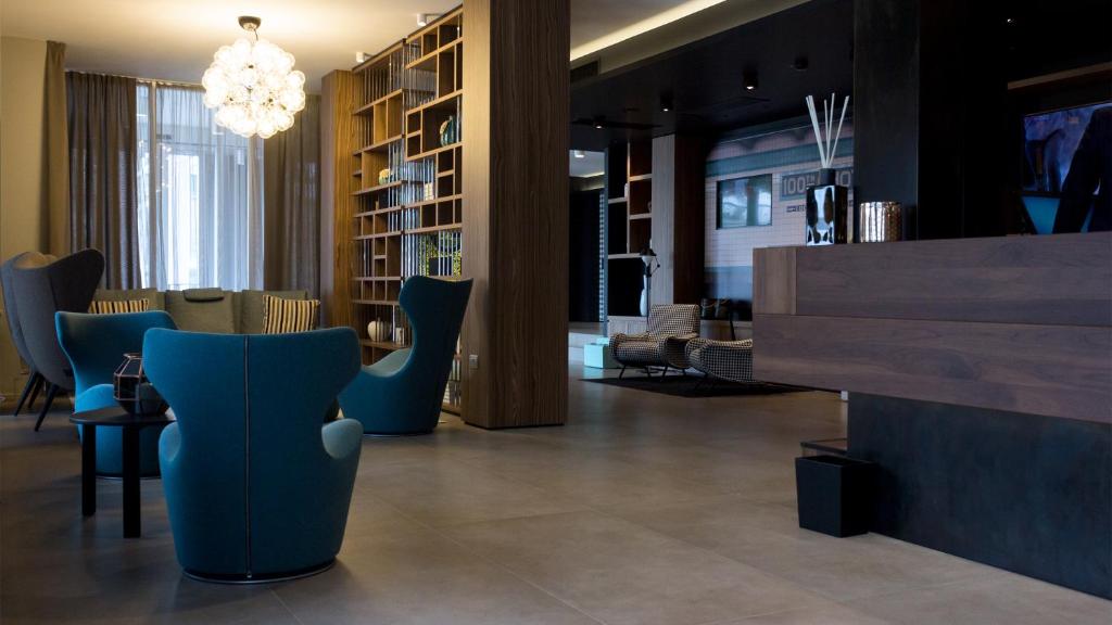 un hall avec des chaises bleues et un lustre dans l'établissement G Hotel Pescara, à Pescara