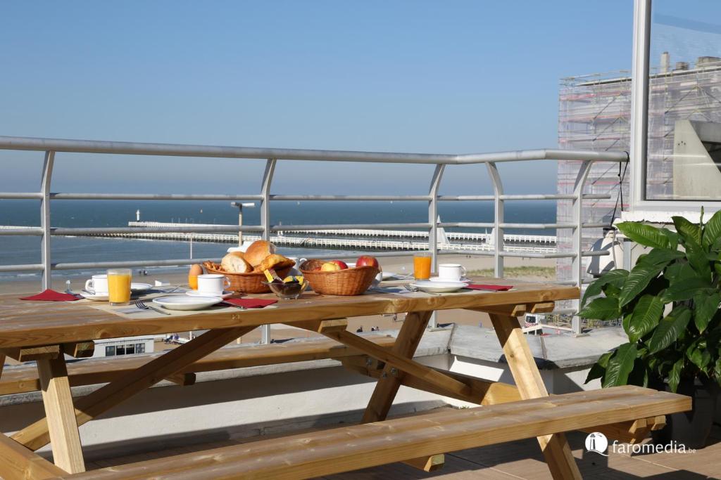 a picnic table on a balcony with a view of the ocean at Hotel Uilenspiegel in Nieuwpoort
