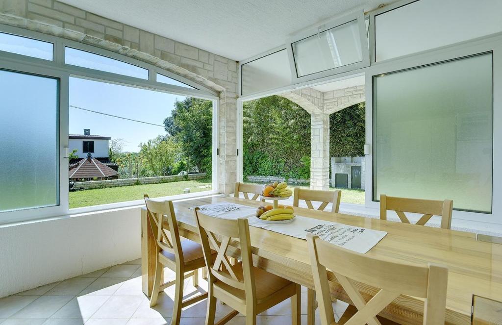 jadalnia ze stołem i oknami w obiekcie Holiday Home Lorena w mieście Premantura