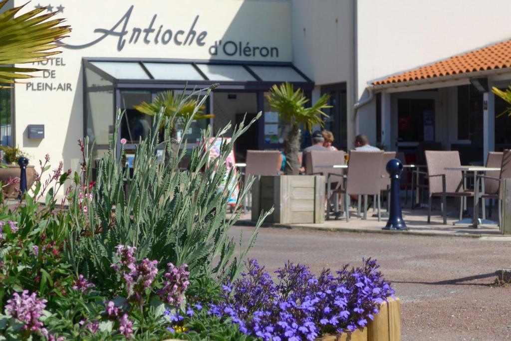 un jardín con flores púrpuras frente a un restaurante en Camping Antioche D'Oléron en La Brée-les-Bains